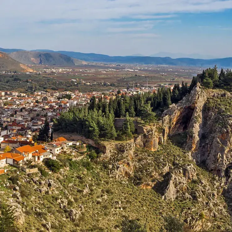 Aerial panoramic view of Livadeia town nestled in a green valley with rolling hills 