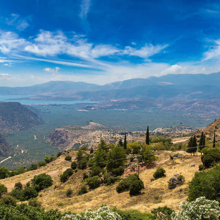 Panoramic view of Amfissa valley with lush greenery, rock hills, and the Gulf of Corinth in the distance