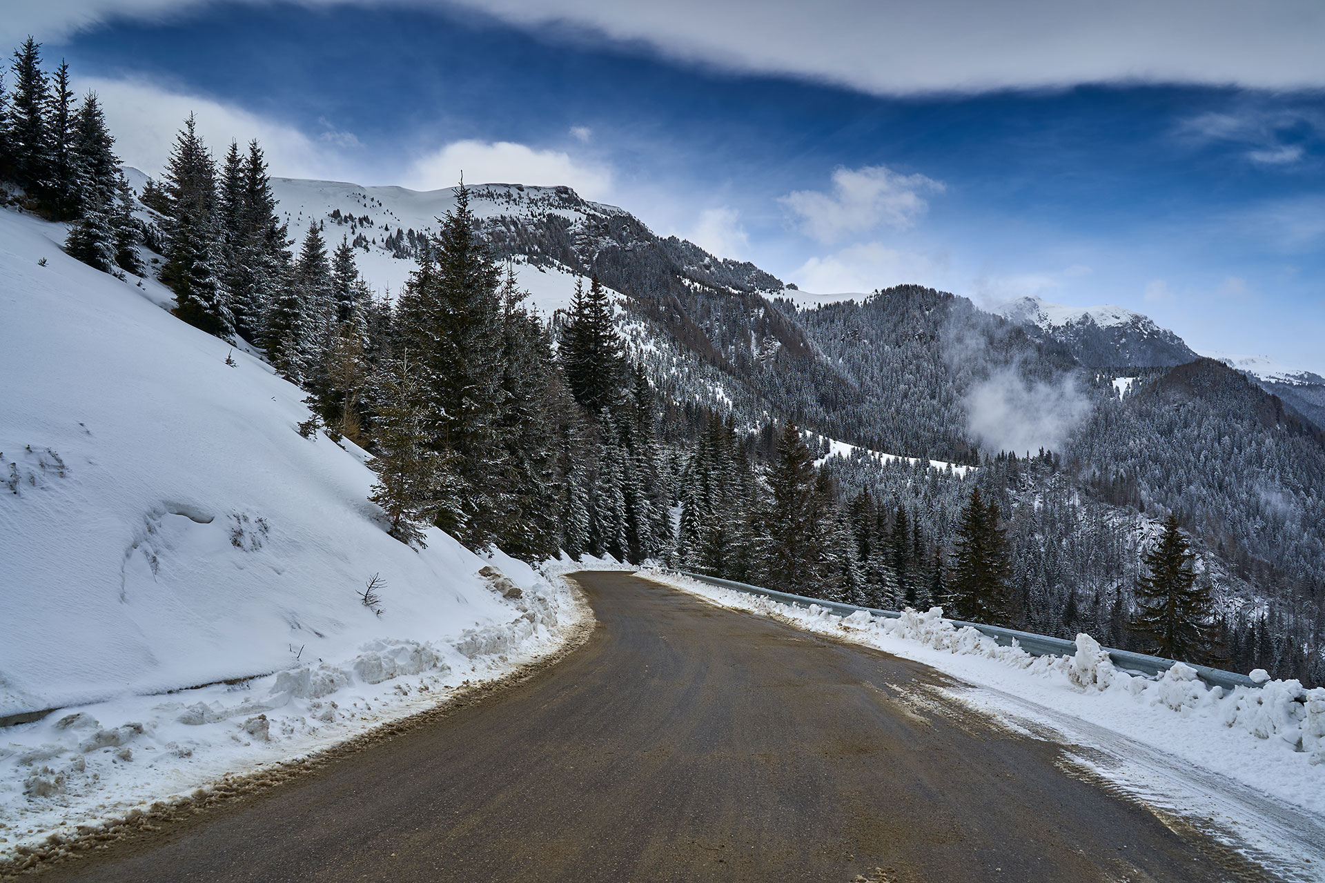 Snowy mountain road surrounded by pine trees leading to Parnassos slopes