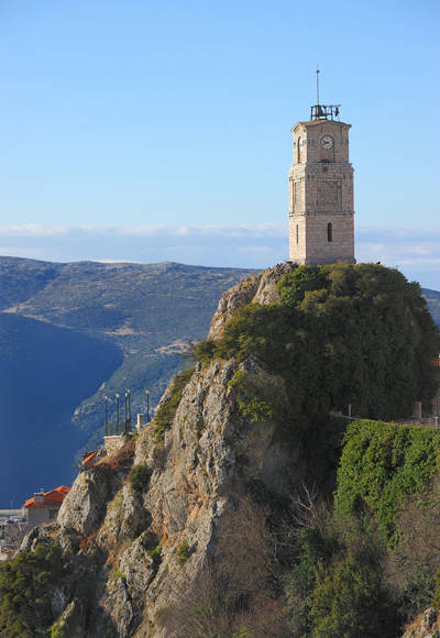 Historic clock tower of Arachova perched on a rocky hill with mountain views