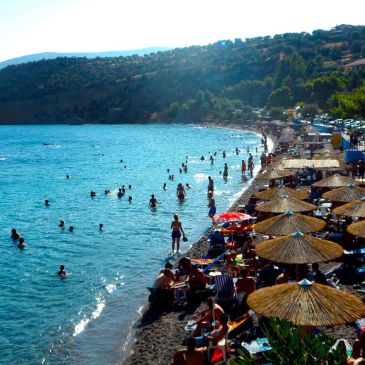 Busy Antikira beach with people swimming and relaxing along the clear blue sea