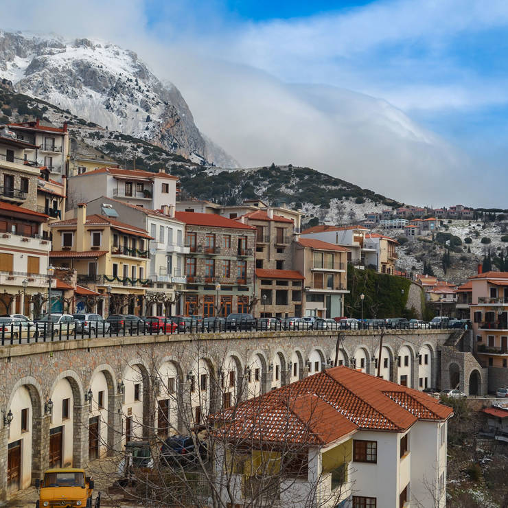 Charming view of Arachova village with stone houses and snowy Mount Parnassus in the background